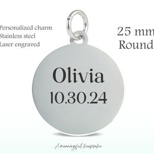 May include: A round, stainless steel charm with the name "Olivia" and the date "10.30.24" engraved in black. The charm is 25 mm in diameter and includes a clasp. The text "Personalized charm", "Stainless steel", and "Laser engraved" are also visible.
