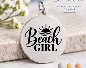 May include: A round stainless steel charm featuring a laser-engraved design of a sun rising over waves with the text Beach GIRL. The charm includes a silver jump ring at the top. Text on the image reads Stainless Steel LASER ENGRAVED CHARMS.