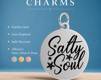 May include: A round stainless steel charm with a silver finish featuring the laser engraved text Salty Soul in a black script font, accented with small star and starfish icons. The charm includes a jump ring at the top for attachment purposes.