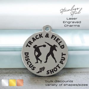 May include: A silver charm with a black and white image of two athletes competing in track and field events. The charm is engraved with the words "Track & Field" and "Discus Shot Put".