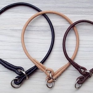 Three round leather slip collars. One black, one natural and one brown. All with chrome rings.