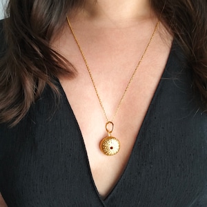 Op de afbeelding: Een gouden ketting met een zee-egel hanger. De hanger is een gedetailleerde, realistische weergave van een zee-egel.
