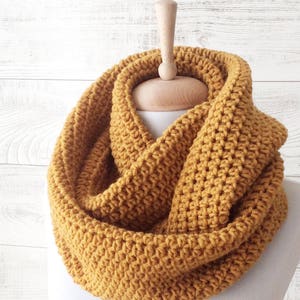 May include: A mustard yellow crocheted infinity scarf. The scarf is made with a simple stitch and is a great accessory for fall and winter.