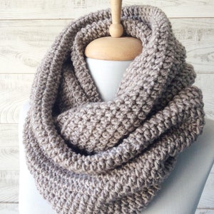 May include: A brown knitted infinity scarf. The scarf is made of a soft, chunky yarn and is perfect for keeping warm in the winter.