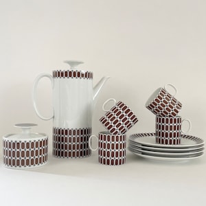 May include: A white porcelain tea set with a brown geometric pattern. The set includes a teapot, sugar bowl, creamer, four cups, and four saucers.