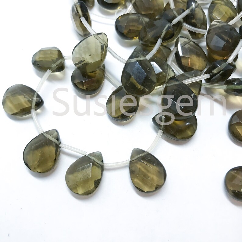 May include: A strand of faceted smoky quartz gemstone beads in a teardrop shape. The beads are strung on clear elastic cord.