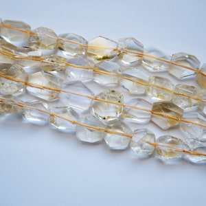 May include: A strand of faceted, clear quartz beads with golden inclusions. The beads are strung on a thin, golden thread.