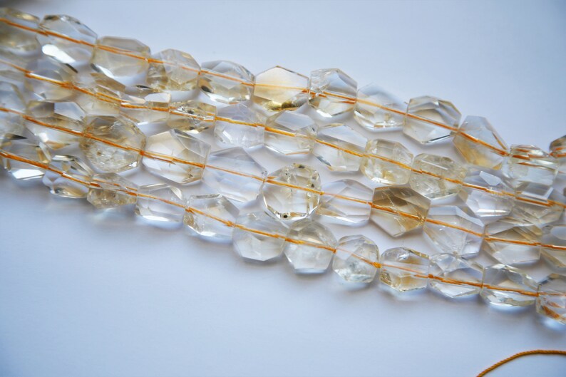 May include: A strand of faceted, clear quartz beads with golden inclusions. The beads are strung on a thin, golden thread.
