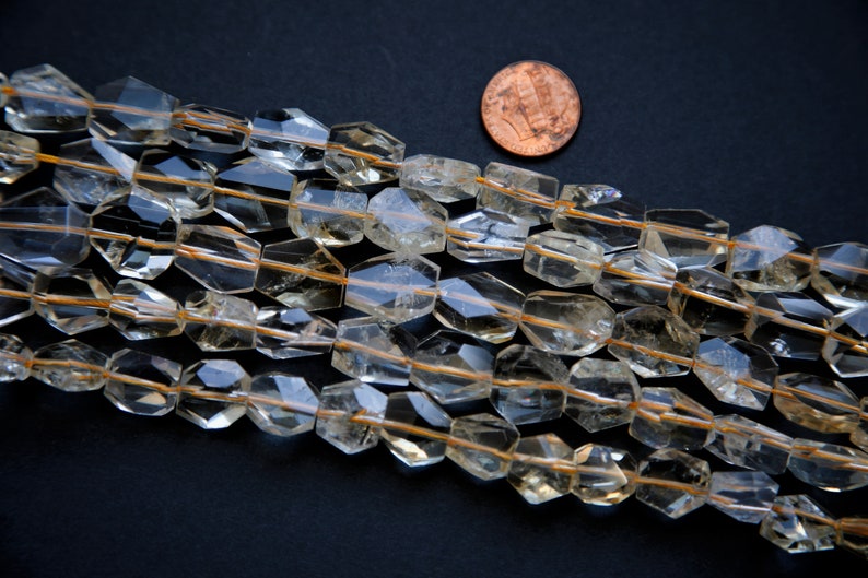 May include: A strand of faceted, clear quartz beads with a golden hue. The beads are strung on a thin wire and are approximately 1/2 inch in diameter.