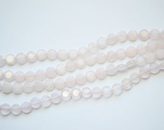 May include: A strand of pale pink rose quartz beads. The beads are faceted and have a slightly translucent appearance.