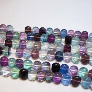 May include: A strand of round, iridescent fluorite beads in shades of purple, blue, green, and white. The beads are strung on a white thread.