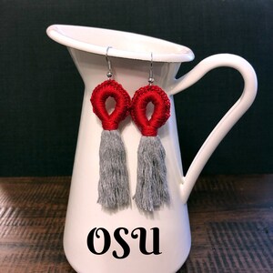 May include: Red and gray crocheted tassel earrings. The earrings are hanging from a white pitcher with the word "OSU" written on the side.