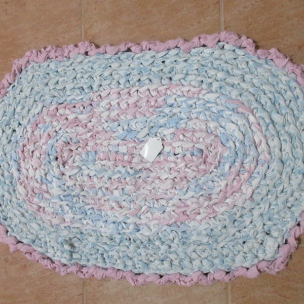 Crocheted rectangle rag rug. Made by my Great grandaughter. Has pastel colors of blue, pink and teal.   Measures 21 by 33 inches.