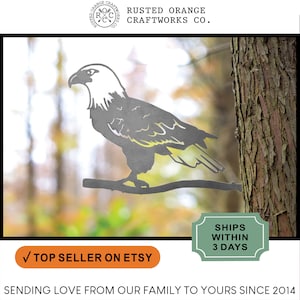 May include: Metal silhouette of a bald eagle perched on a branch, with a rustic brown background. The eagle is facing left and has a detailed design. The text "RUSTED ORANGE CRAFTWORKS CO." is at the top of the image.