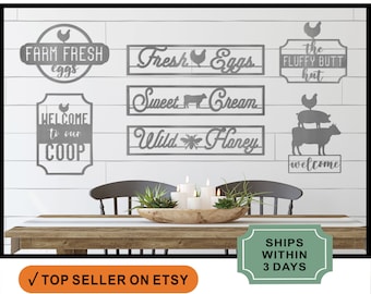 May include: A set of metal farmhouse signs with a rustic finish. The signs feature various farm-related phrases, including "Farm Fresh Eggs", "Sweet Cream", "Wild Honey", and "Welcome to our Coop". The signs are displayed on a wooden table with a rustic farmhouse decor theme.