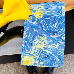 May include: A blue and yellow fabric pocket square with a swirling, abstract pattern reminiscent of Vincent van Gogh's "Starry Night".