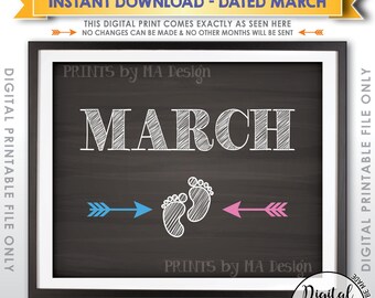 May include: A digital printable sign featuring a dark chalkboard background with the white text MARCH. Below the text are white baby footprints flanked by a blue arrow pointing left and a pink arrow pointing right. The design includes the text PRINTS by MA Design.