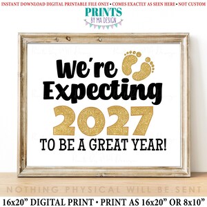 Puede incluir: Impresión digital enmarcada con el texto "We're Expecting 2027 To Be A Great Year!" en letras negras y doradas brillantes. La impresión incluye huellas de bebé doradas con purpurina. Disponible en 40,64 x 50,8 cm o 20,32 x 25,4 cm.