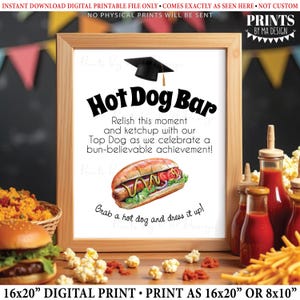 May include: A framed digital print with the words "Hot Dog Bar" and a graphic of a hot dog. The print includes the text "Relish this moment and ketchup with our Top Dog as we celebrate a bun-believable achievement!" and "Grab a hot dog and dress it up!"