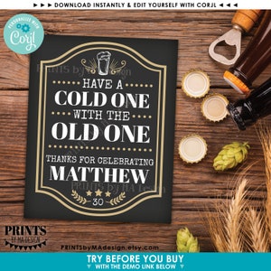 Pu&ograve; includere: Un cartello nero in ardesia con bordo dorato e testo che recita "Have a Cold One with the Old One. Thanks for celebrating Matthew. Prints by MA Design 30". Il cartello &egrave; su una superficie di legno con tappi di bottiglia e un luppolo.