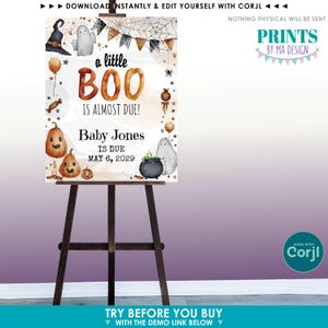 Op de afbeelding: Een Halloween-thema baby aankondigingsbord op een houten ezel. Het bord bevat illustraties van pompoenen, geesten en een heksenhoed. De tekst luidt "a little BOO is almost due!" en bevat de naam van de baby en de vervaldatum.