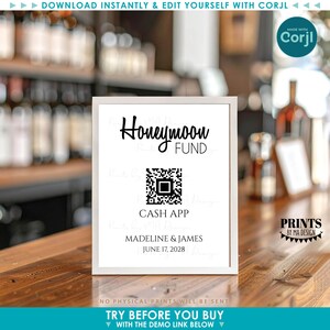 May include: A framed sign with the words "Honeymoon Fund" in elegant script. Below is a QR code and the text "Cash App," followed by names and a date. The sign is white with black text and is displayed on a wooden surface.