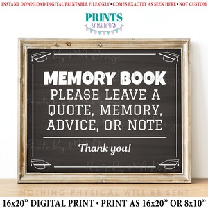 May include: A black chalkboard sign with white text that reads "Memory Book Please Leave a Quote, Memory, Advice, or Note Thank you!" The sign is framed in a brown wooden frame and has a graduation cap design in the top corners.