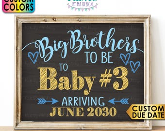 May include: A digital print in a wooden frame featuring a dark chalkboard background with light blue and yellow text. The text reads Big Brothers to be Baby #3 arriving June 2030. The design includes light blue heart icons and arrows.