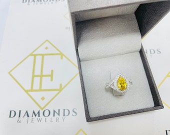 May include: A pear-shaped yellow diamond engagement ring with a halo of smaller diamonds set in a silver band. The ring is in a gray ring box.