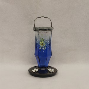 Glass Hummingbird feeder, a variegated blue to clear jar, Hand painted with Yellow daisies and white blossoms.