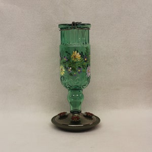 Antique Green Hummingbird feeder hand painted with Gerber Daisies and Purple Blossoms. Holds 24 oz and 4 feeding ports