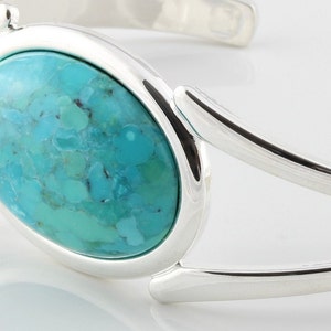 Pode incluir: Um bracelete de prata com uma grande pedra oval turquesa engastada no centro.