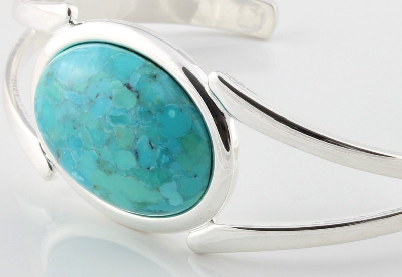 Pode incluir: Um bracelete de prata com uma grande pedra oval turquesa engastada no centro.