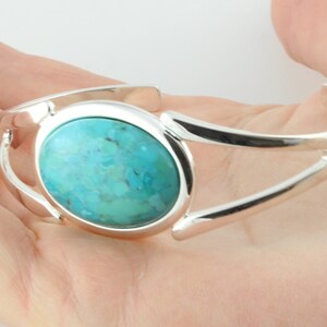 Pode incluir: Um bracelete de prata com uma pedra turquesa caboch&atilde;o engastada em um bezel circular.