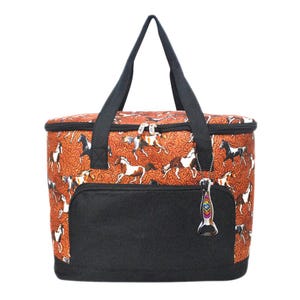 May include: An insulated tote bag with a black base and handles. The bag features a repeating pattern of running horses on a rust-colored background. A black pocket is on the front. A bottle opener hangs from the zipper.