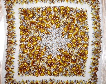Peut inclure: Un foulard en soie beige avec un motif floral. Les fleurs sont brunes et jaunes avec un centre blanc. Le foulard a une bordure à franges.