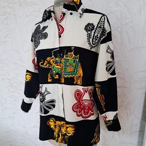 May include: A white and black long-sleeved button-up shirt with a colorful patterned design featuring elephants, paisley, and floral motifs.