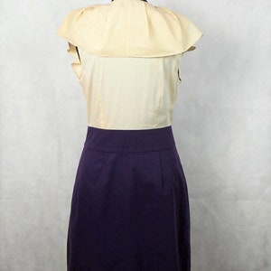 May include: A sleeveless dress with a yellow top and a purple skirt. The top has a large ruffle collar.