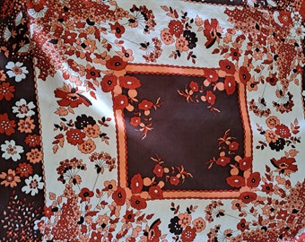 May include: A brown and white fabric with a floral pattern. The fabric has a square design in the center with a brown background and a white border. The border is decorated with a red and orange floral pattern.