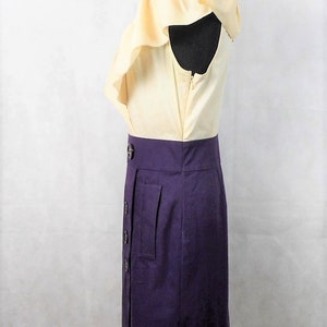 May include: A yellow and purple dress with a ruffled neckline and a button-up front. The dress has a fitted bodice and a skirt that falls to the knee.