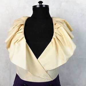 May include: A white ruffled collar with a V-neckline on a dress. The dress is a two-tone design with a purple bottom and a white top.