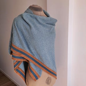 Könnte beinhalten: Ein blauer und weißer Schal mit Fischgrätenmuster und orangefarbenen und blauen Streifen an den Rändern.
