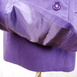 May include: A purple jacket with a button closure and a pocket on the inside of the sleeve.