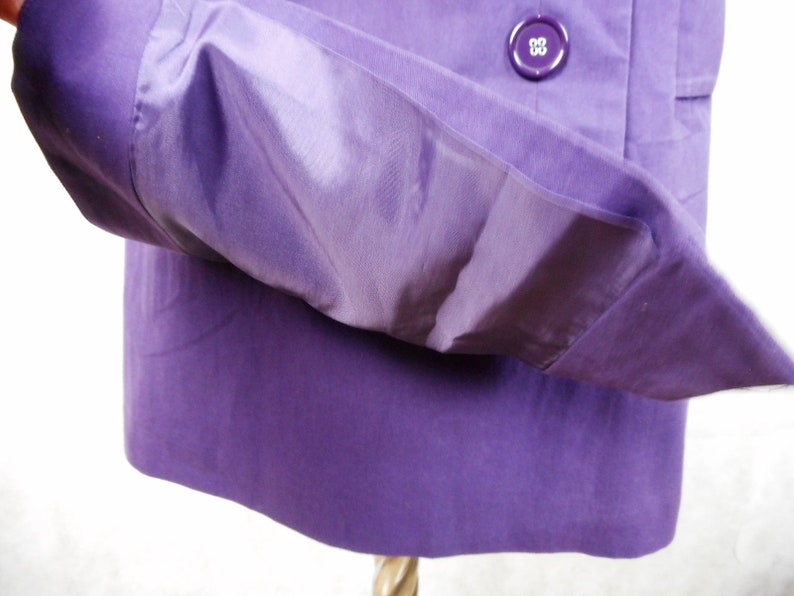 May include: A purple jacket with a button closure and a pocket on the inside of the sleeve.