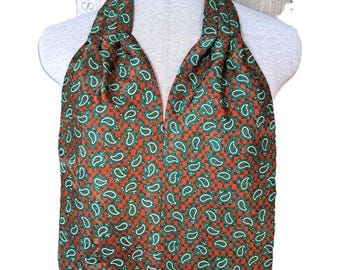 May include: A paisley patterned vest in shades of red, green, and white. The vest is displayed on a mannequin. The paisley pattern is a repeating design of curved, teardrop-shaped motifs. The vest has a V-neck and a tailored fit.