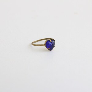May include: A gold ring with a heart-shaped blue gemstone.