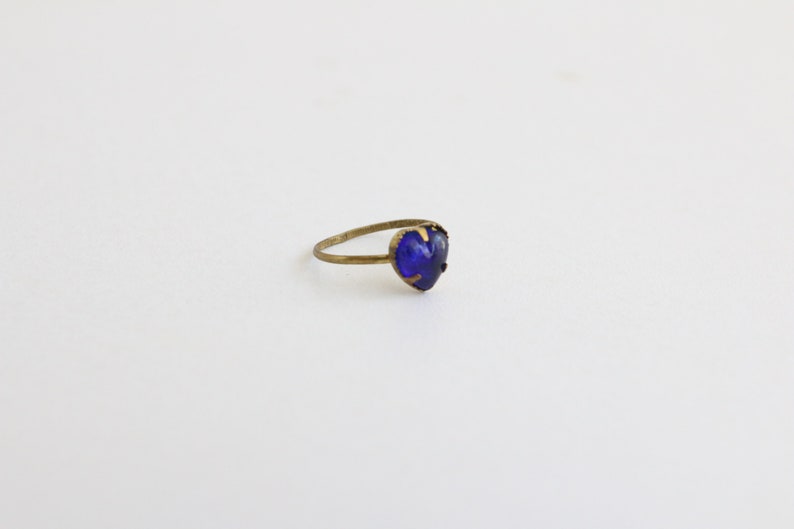 May include: A gold ring with a heart-shaped blue gemstone.
