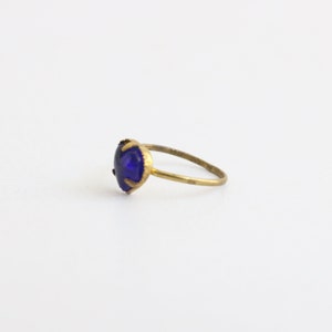May include: A gold ring with a dark blue heart-shaped gemstone.
