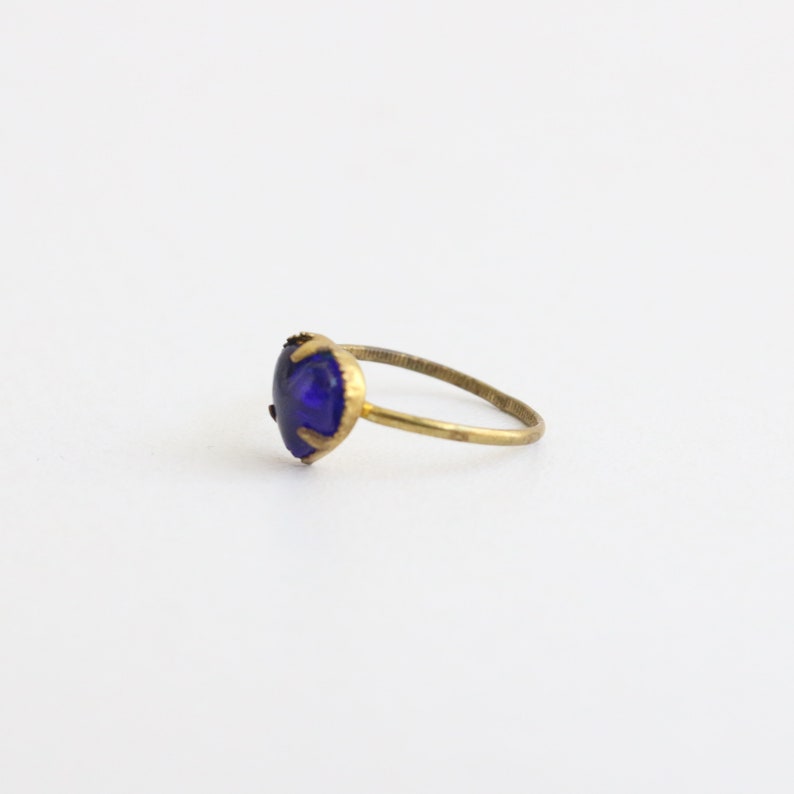 May include: A gold ring with a dark blue heart-shaped gemstone.