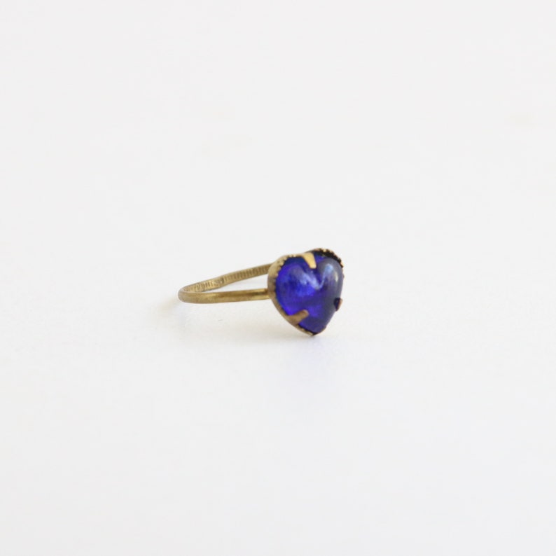 May include: A gold ring with a heart-shaped blue gemstone.